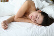 © H_Ko - Beautiful woman sleep and smile with her hand under her cheek. Sell white and soft bedding from best fabric.