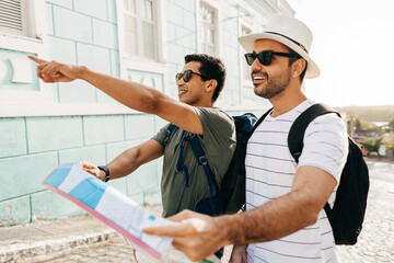 Wall Mural - Two happy male tourists using map. Travel and love concept in Latin America