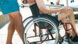 Disabled man at beach swimming on a wheelchair with assistance help on an accessible ramp.