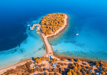 Aerial view of beutiful small island in sea bay at sunset in autumn in Murter, Croatia. Top view of clear blue water, orange trees, mountain, sandy beach, boats and yachts in fall. Tropical landscape