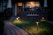 © Rachel Bellinsky/Stocksy - A lighted brick path leading to a house with glowing windows at night