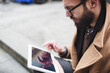© Michela Ravasio/Stocksy - Young man using his digital tablet outdoors