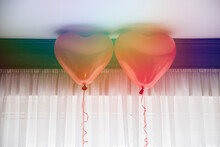 Double Exposure Of Two Red Heart Balloons Exposed On Rainbow Light Reflection