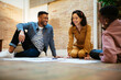 © BONNINSTUDIO/Stocksy - Happy young colleagues sitting on floor and discussing project
