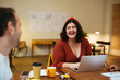 © BONNINSTUDIO/Stocksy - Happy woman sitting at table and talking with colleague