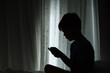© Rob and Julia Campbell/Stocksy - Young boy playing games on mobile phone in dark room.