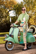 © SuperStock - Portrait of woman sitting on vespa outside in a driveway.