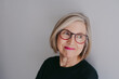 © Rob and Julia Campbell/Stocksy - Portrait of mature woman wearing glasses on seamless white studio background