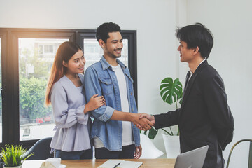 buy house / home moving and relocation concept. Happy asian couple shaking hands with real estate agent.