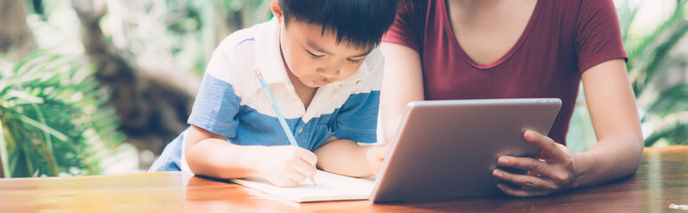 Wall Mural - Son using digital tablet computer for study and learn to internet online with mother together, education from home, family recreation, mom teach boy and homework, lifestyle concept, banner website.