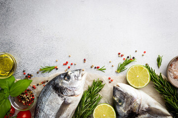 Fresh ready to cook raw bream fish dorado with ingredients and seasonings like rosemary, salt, pepper, lime and olive oil, top view