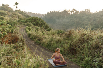 Wall Mural - Young caucsian woman practicing yoga pose at the park ,  meditation have good benefits for health. Photo concept for Sport and Healthy lifestyle.