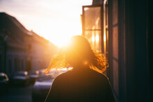 Silhouette Of A Woman With Hair In The Rays Of The Setting Sun On The Street During Sunset