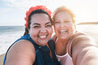 © DisobeyArt - Curvy women friends taking selfie on the beach with sunset in background - Happy plus size body female having fun together - Curves and confident concept