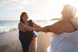 © DisobeyArt - Plus size women dancing on the beach having fun during summer vacation - Curvy female laughing together - Overweight body and happiness concept - Focus on right woman face