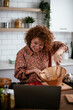 © JustLife - Young woman is reading a recipe while cooking. Beautiful woman with curly hair enjoying in the kitchen.