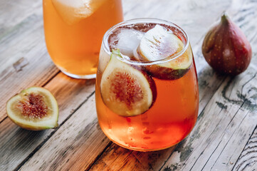 Wall Mural - Cold lemonade cocktail with figs on rustic wooden background