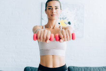 Selective Focus Of Brunette Sportswoman Working Out With Pink Dumbbells At Home