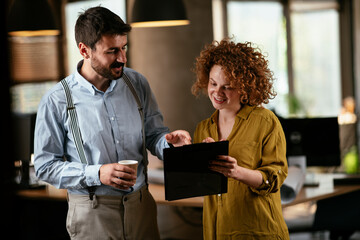  Businesswoman and businessman discussing work in office. Two friends in working together.