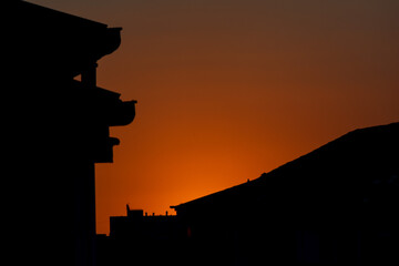 Silhouette of rooftops in the sunset. Orange sky