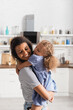 © LIGHTFIELD STUDIOS - young african american woman with closed eyes holding daughter on hands in kitchen