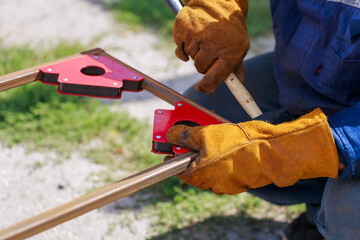 Working auxiliary tools in the hands of a worker welder. Using a magnetic welding angle in work to fix metal