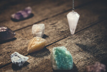 Crystal Pendulum With Healing Gemstones On Wooden Table, Spirituality And Esoteric