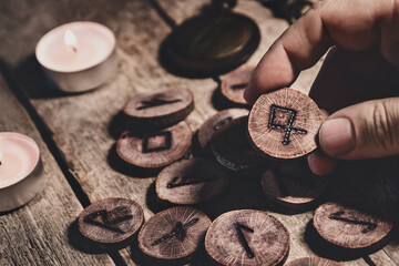 Hand holding wooden runes or futhark, esoteric and spirituality, reading and fortuneteller