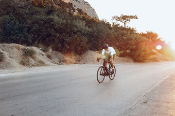 Wall Mural - Man cyclist pedaling on a road bike outdoors in sun set