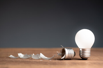 Glowing small light bulb and the broken one on the table, concept of fail and success, bad and good idea, problem and solution, learning from mistake or pros and cons object