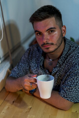 Canvas Print - Shallow focus shot of a young brunette male drinking a hot drink