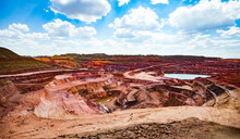 Aluminium Ore (bauxite Clay) Mining In Quarry. Mining Machines And Heaps Of Color Empty Stones On Horizon. Blue Sky With Clouds.