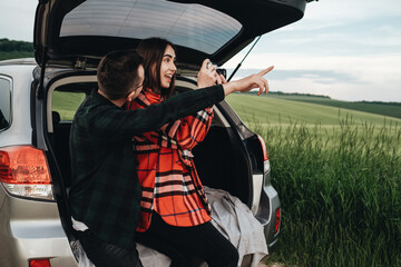 Young Beautiful Couple Sitting in the Car Trunk and Enjoying the Roadtrip