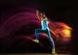 © master1305 - Professional male runner training isolated on black studio background in mixed light. Man in sportsuit practicing in run or jogging. Healthy lifestyle, sport, workout, motion and action concept.