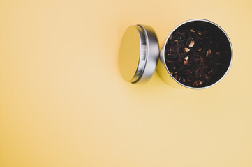 Sticker - Closeup shot of dried hibiscus tea leaves in a metal container on a yellow surface