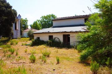 large low abandoned white house without doors and windows in an isolated clearing in nature