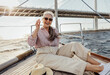 © Artem Varnitsin - Happy mature woman resting on a yacht bow. Smiling female enjoying boat trip wearing sunglasses.