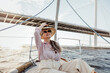 © Artem Varnitsin - Mature woman in sunglasses puts on hat sitting on a sailboat at sunny day