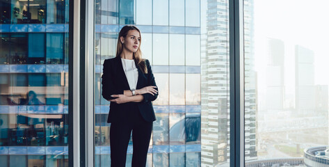 Wall Mural - Serious female entrepreneur standing with folded arms in office