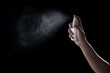 Hand spraying antiseptic against virus isolated on black background