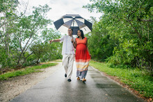 Couple Holding Umbrella On Boardwalk