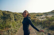 © denni/Stocksy - Young woman tunes around during her workout in the dunes