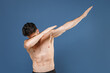 © ViDi Studio - Young bearded fitness sporty strong guy bare-chested muscular sportsman posing isolated on blue wall background studio portrait. Workout sport motivation lifestyle concept. Showing DAB dance gesture.