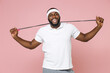 © ViDi Studio - Cheerful young bearded african american fitness sports man in white headband t-shirt hold skipping rope looking camera spending time in gym isolated on pastel pink color background studio portrait.