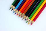 Fototapeta Tęcza - Colored pencils on white background. Many different colored pencils. Color pencil. Pencils are sharp. Pencils placed diagonally in the upper-right corner. Close-up. Copy space. Background. Flatlay