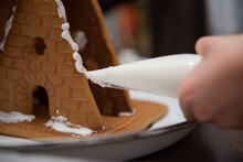 A Child Squeezes Frosting Onto A Gingerbread House