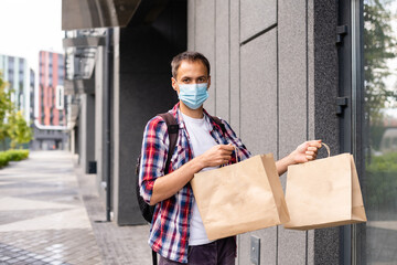 Wall Mural - Delivery man holding paper bag with food, food delivery man in protective mask