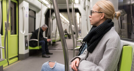 Portrait of lovely girl commuting on almost empty public subway train. Staying at home and social distancing recomented due to corona virus pandemic outbreak.