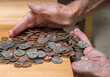 © steheap - Hundreds of US coins being gathered into hands on wooden table as concept for hoarding during shortage of loose change