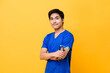 © Atstock Productions - Young handsome Asian male doctor smiling and doing arms crossed gesture isolated on yellow background